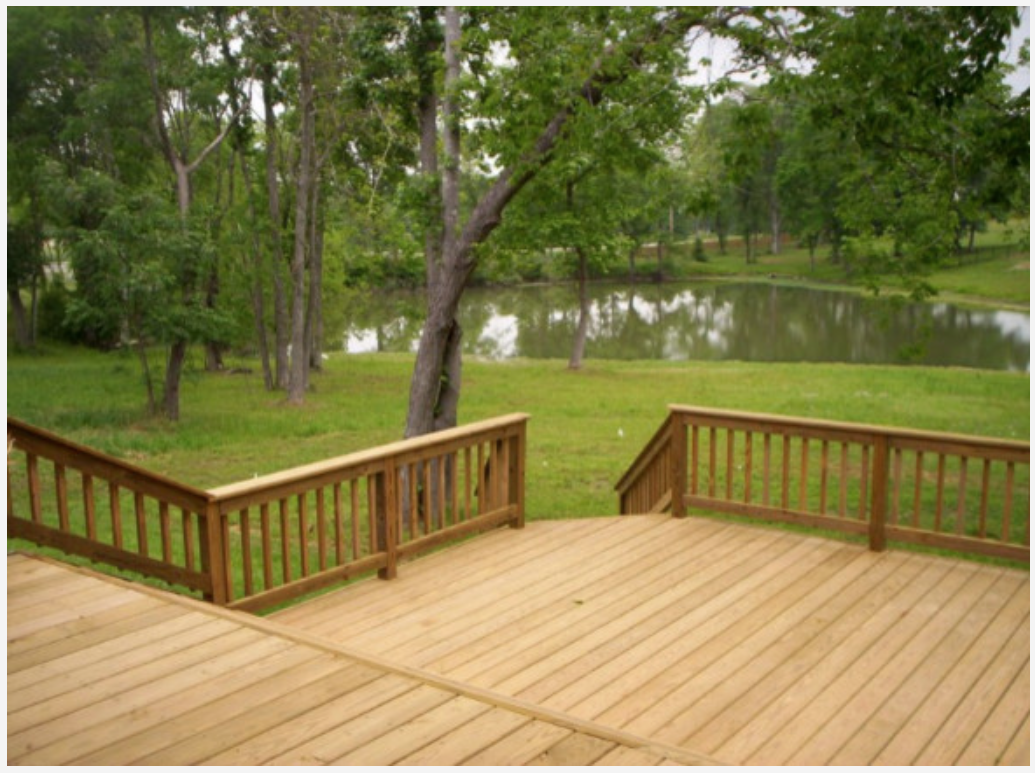 Wood backyard deck overlooking a pond, built by Cavalier Custom Decks in Coldspring, TX